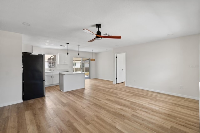 unfurnished living room featuring ceiling fan, sink, and light wood-type flooring