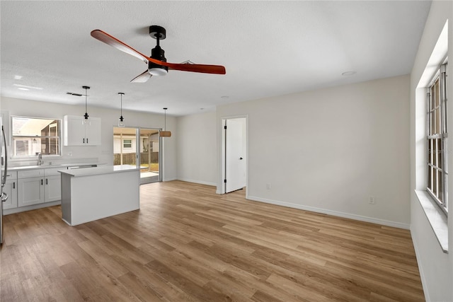 kitchen featuring ceiling fan, white cabinetry, decorative light fixtures, a kitchen island, and light wood-type flooring