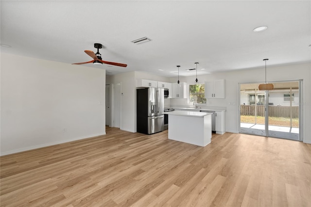 kitchen featuring a kitchen island, light hardwood / wood-style flooring, decorative light fixtures, white cabinets, and appliances with stainless steel finishes