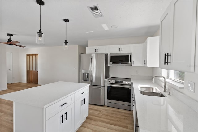 kitchen featuring appliances with stainless steel finishes, a center island, white cabinetry, and sink