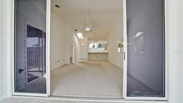 unfurnished living room with lofted ceiling with skylight, carpet, and ceiling fan with notable chandelier