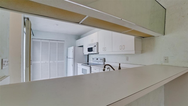 kitchen featuring white cabinets and white appliances