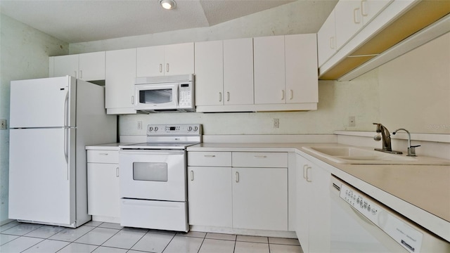 kitchen featuring white cabinetry, sink, white appliances, and light tile patterned floors