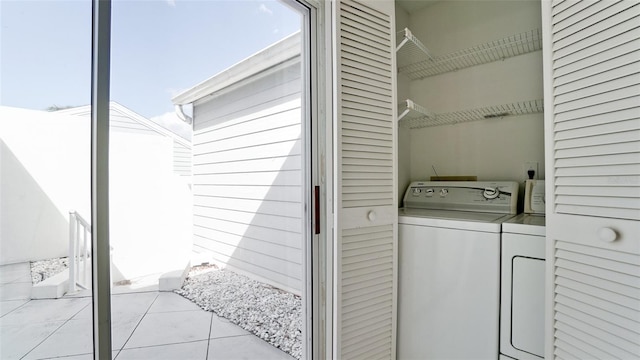 clothes washing area featuring washer and clothes dryer and light tile patterned floors