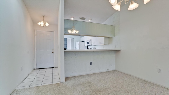 kitchen with white appliances, light carpet, vaulted ceiling, and a notable chandelier