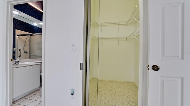 spacious closet featuring sink and light tile patterned flooring