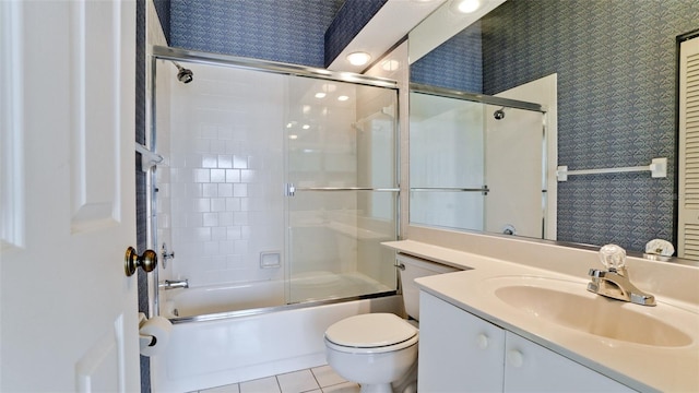 full bathroom with bath / shower combo with glass door, vanity, tile patterned floors, and toilet