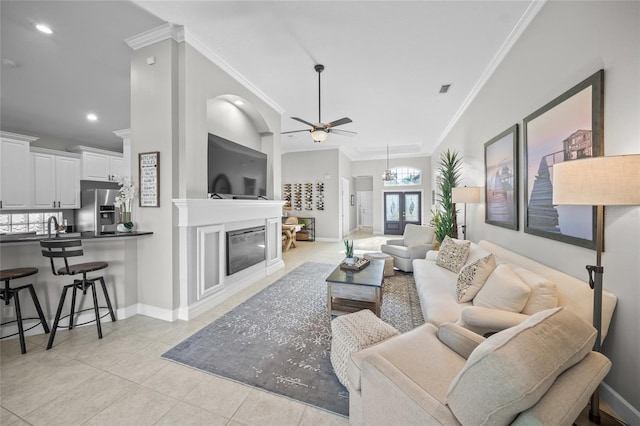 living room with a glass covered fireplace, crown molding, baseboards, and light tile patterned floors