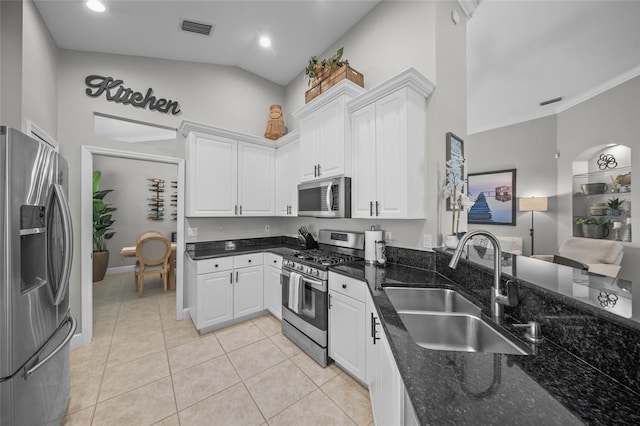 kitchen featuring visible vents, appliances with stainless steel finishes, white cabinets, a sink, and dark stone counters