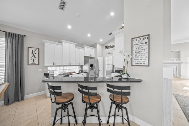 kitchen featuring light tile patterned flooring, a peninsula, visible vents, white cabinets, and stainless steel fridge with ice dispenser