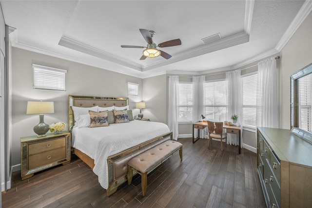 bedroom with baseboards, visible vents, a raised ceiling, ornamental molding, and dark wood-style flooring