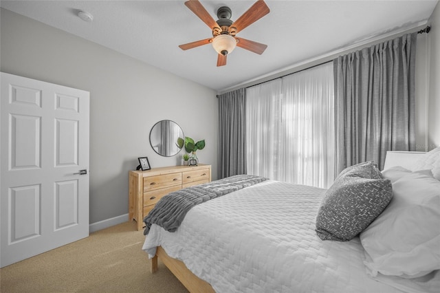 bedroom with light carpet, ceiling fan, and baseboards