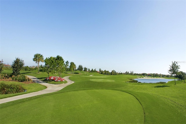 view of community featuring view of golf course, a water view, and a yard