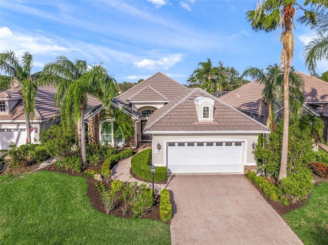 view of front of home featuring a garage, decorative driveway, a tiled roof, and stucco siding