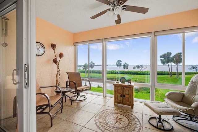 sunroom / solarium with ceiling fan and a water view