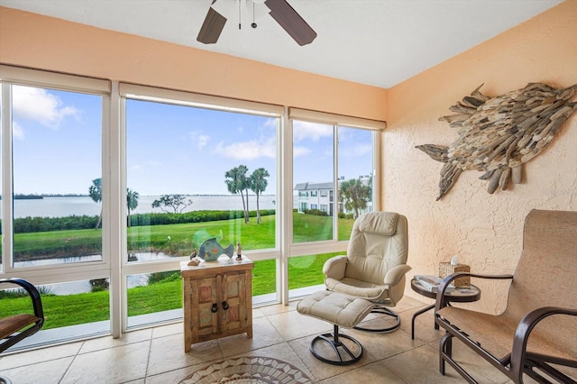 sunroom featuring ceiling fan and a water view