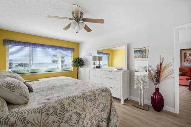 bedroom with ceiling fan, light hardwood / wood-style flooring, and a textured ceiling