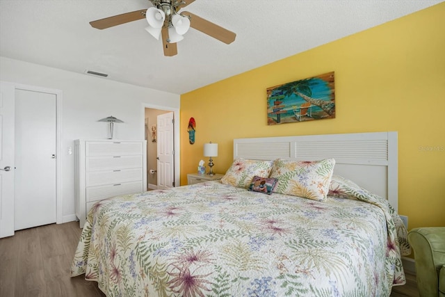 bedroom with a textured ceiling, light hardwood / wood-style flooring, and ceiling fan