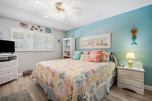 bedroom with light wood-type flooring, a textured ceiling, and ceiling fan