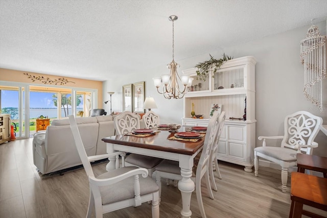 dining room with an inviting chandelier, a textured ceiling, and light hardwood / wood-style flooring