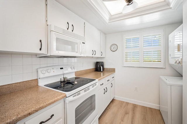 kitchen featuring white appliances, crown molding, white cabinetry, backsplash, and a tray ceiling