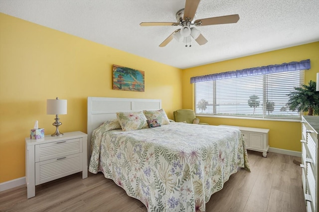 bedroom with a textured ceiling, light hardwood / wood-style floors, and ceiling fan