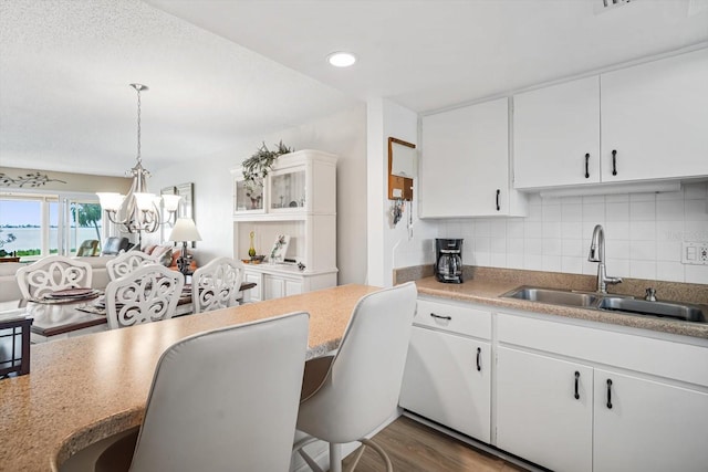 kitchen with white cabinetry, dark wood-type flooring, sink, and pendant lighting