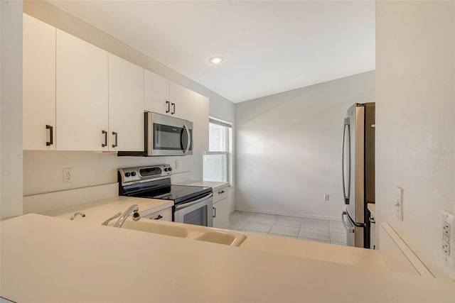 kitchen with stainless steel appliances, white cabinets, light tile patterned floors, and kitchen peninsula