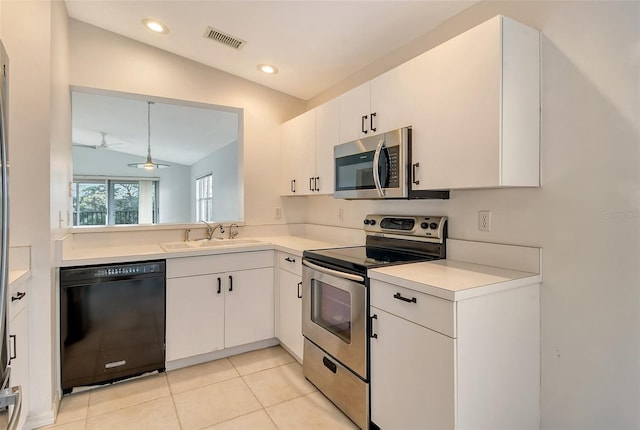 kitchen featuring stainless steel appliances, sink, light tile patterned floors, white cabinets, and vaulted ceiling