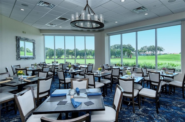 dining area with a drop ceiling and a notable chandelier