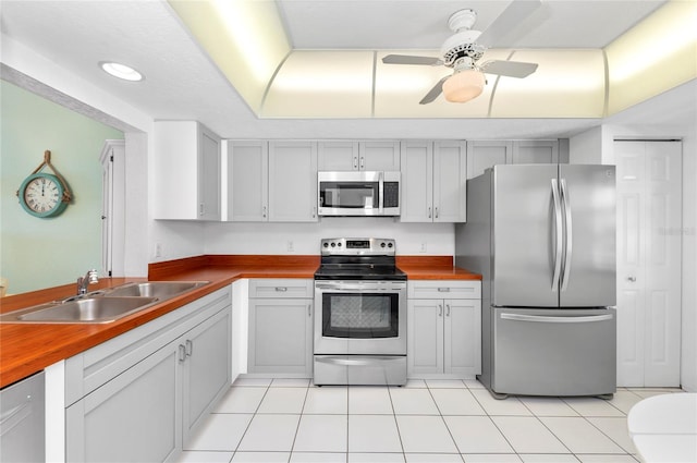 kitchen featuring appliances with stainless steel finishes, sink, ceiling fan, and wood counters