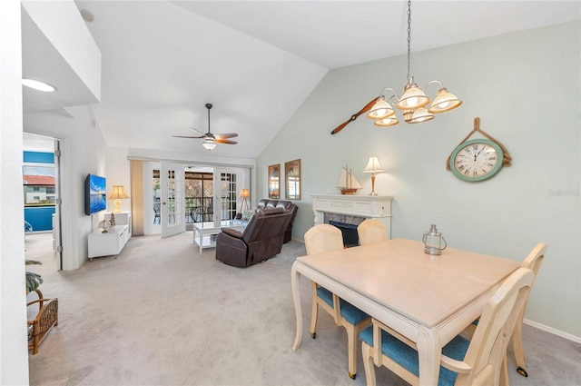 dining area with french doors, ceiling fan with notable chandelier, lofted ceiling, and light colored carpet