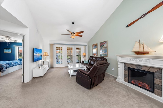 carpeted living room featuring ceiling fan, a stone fireplace, high vaulted ceiling, and french doors