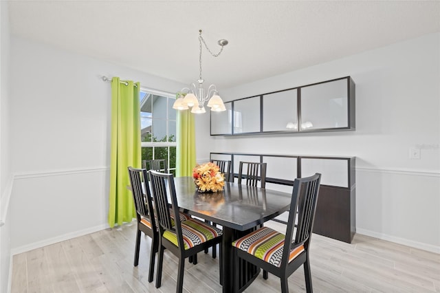 dining space with light wood-type flooring and a chandelier