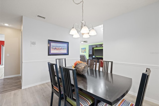 dining area featuring a textured ceiling, light hardwood / wood-style flooring, and a notable chandelier