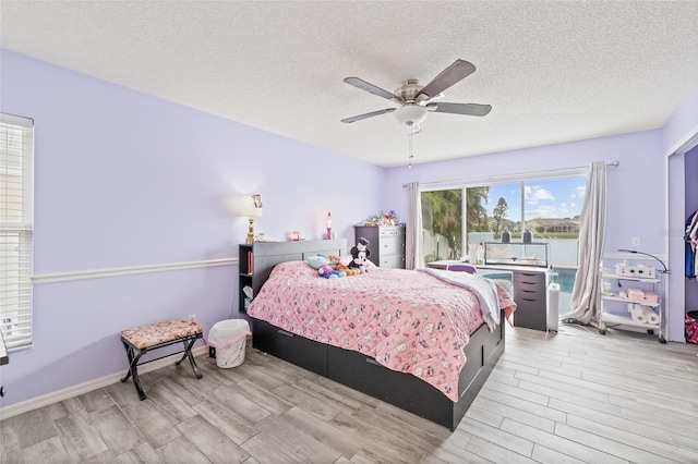 bedroom with light hardwood / wood-style floors, a textured ceiling, and ceiling fan