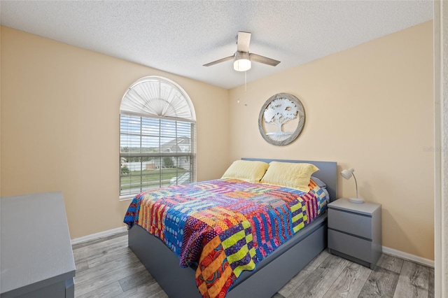 bedroom with ceiling fan, a textured ceiling, and light hardwood / wood-style flooring