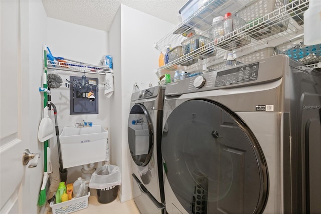 clothes washing area featuring a textured ceiling, washer and clothes dryer, and sink