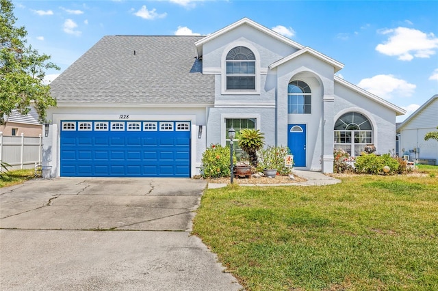 traditional-style home featuring fence, a garage, concrete driveway, a front yard, and roof with shingles