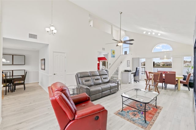 living room featuring stairway, visible vents, light wood-style floors, and ceiling fan with notable chandelier