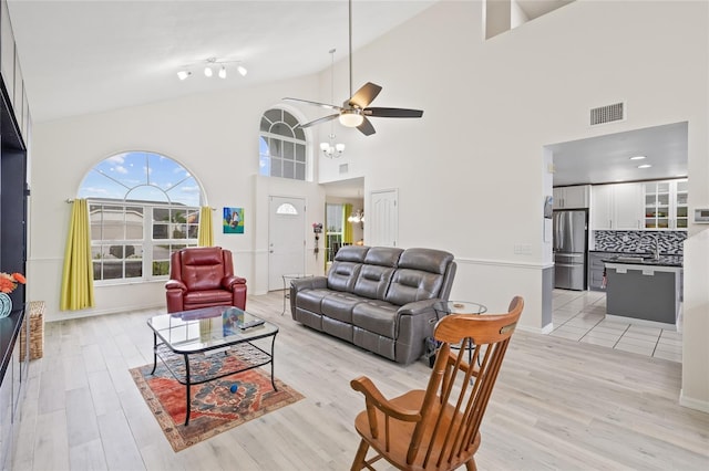 living room featuring visible vents, light wood-style floors, ceiling fan, and vaulted ceiling