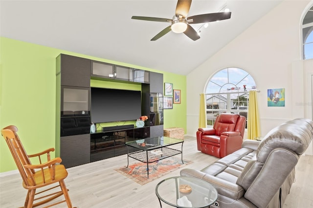 living area with baseboards, light wood-type flooring, high vaulted ceiling, and ceiling fan