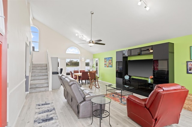 living room featuring high vaulted ceiling, track lighting, stairway, a ceiling fan, and light wood-style floors
