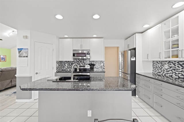 kitchen with light tile patterned flooring, dark stone countertops, a sink, and appliances with stainless steel finishes
