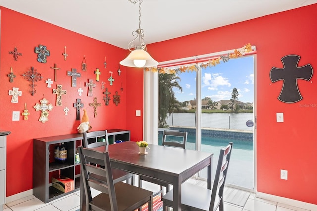 dining area featuring light tile patterned floors, a water view, and baseboards