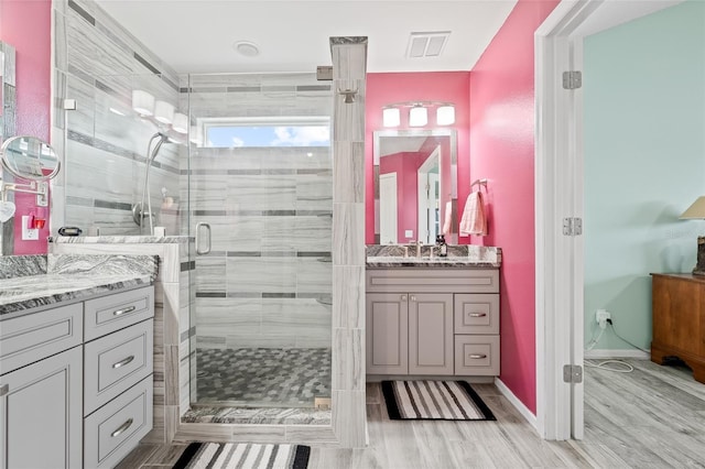 full bath with vanity, baseboards, a stall shower, visible vents, and wood finished floors