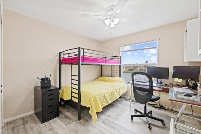 bedroom with a ceiling fan, a textured ceiling, baseboards, and light wood-type flooring