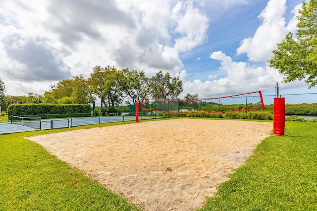 view of home's community with a tennis court, fence, volleyball court, and a yard