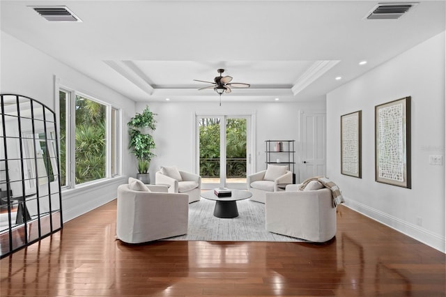 living room with a raised ceiling, ceiling fan, and dark hardwood / wood-style floors