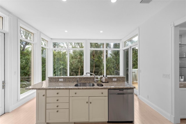 kitchen featuring dishwasher, light hardwood / wood-style floors, light stone counters, and plenty of natural light